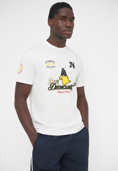 Λευκό βαμβακερό t-shirt με πολύχρωμες εκτυπώσεις, συμπεριλαμβανομένου ενός χαρακτήρα κινουμένων σχεδίων και κείμενο. Κοντά μανίκια και κλασικός στρογγυλός λαιμός.