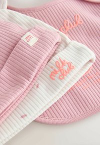Pile de vêtements pour bébé côtelés rose et blanc avec texte brodé "milk club" et petite étiquette "most cute" sur tissu doux.