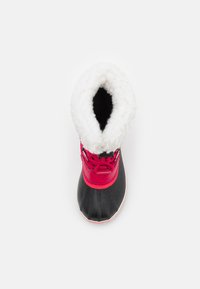 Bota negra impermeable con un grueso forro de piel blanca, área del tobillo en color rosa brillante, patrones cosidos y herrajes para cordones. Forma de punta redondeada.