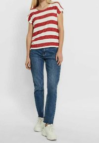 T-shirt à rayures rouges et blanches, à manches courtes, associée à un jean en denim bleu et des baskets blanches. Look décontracté avec un design relax.