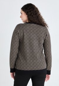 Sweter robiony na drutach z geometrycznym wzorem w odcieniach beżu i czerni. Długie rękawy, okrągły dekolt oraz ściągacze u dołu i na końcach rękawów.
