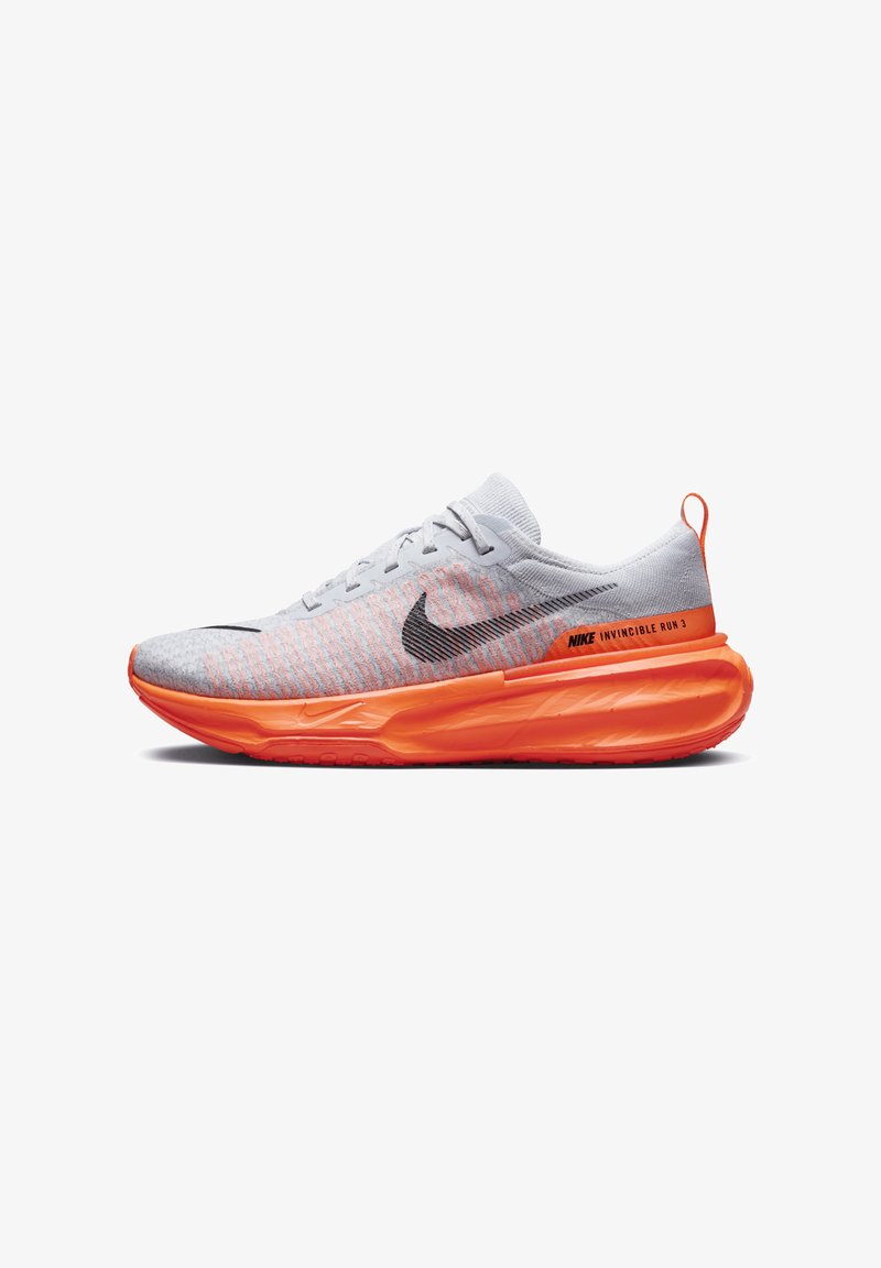 Nike Invincible Run 3 shoe features a light gray knit upper with orange accents, a black swoosh, and a thick, textured orange sole.