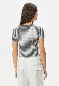 Randig grå och vit kortärmad t-shirt med rund halsringning, med en figurnära design och ribbad textur, kombinerad med högmidjade vita byxor.