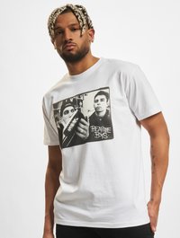 Fehér pamut póló, fekete-fehér grafikával, amely két egyént ábrázol, és a "BEASTIE BOYS" feliratot tartalmazza. Rövid ujjú, kerek nyakú.