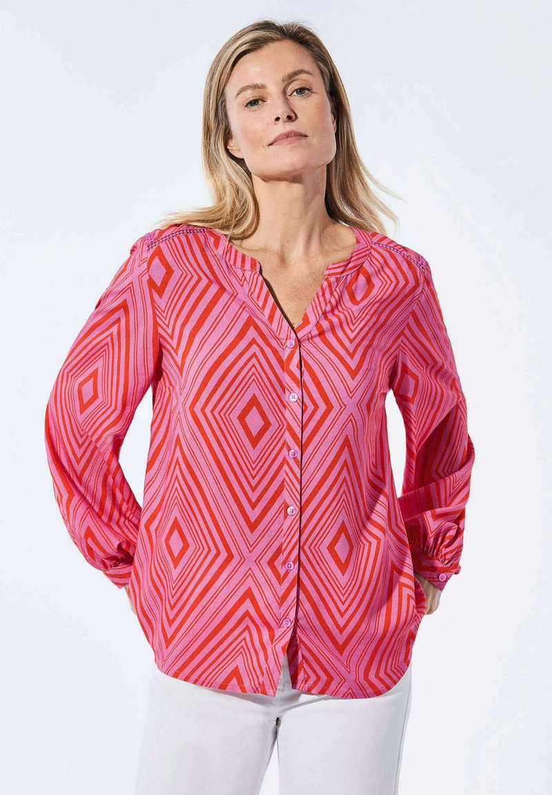 Rode en roze blouse met lange mouwen en een geometrisch ruitpatroon, knoopsluiting aan de voorkant en een v-hals ontwerp. Gemaakt van lichtgewicht stof.