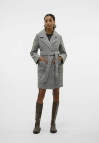 Manteau gris texturé avec un col châle, ceinture à la taille, et deux poches avant, assorti à des bottes marron jusqu'aux genoux.