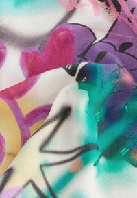Tissu multicolore présentant des motifs de graffiti abstraits dans des teintes de rose, violet, bleu-vert et jaune, avec une surface douce et texturée.