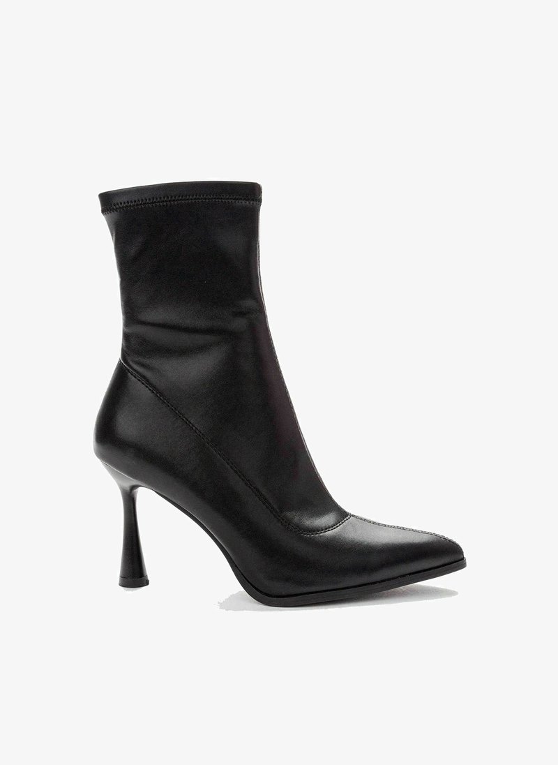 Botín negro de tacón con un diseño de cuero elegante, puntera afilada y una parte superior suave y ajustada. Tacón de aguja ligeramente curvado.