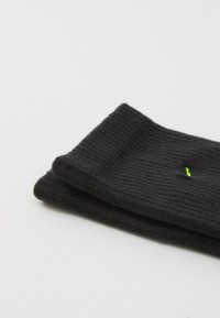 Μαύρες πλεκτές κάλτσες με ριγωτή υφή, με μια μικρή πράσινη λεπτομέρεια. Διπλωμένες προσεκτικά με λείο φινίρισμα.