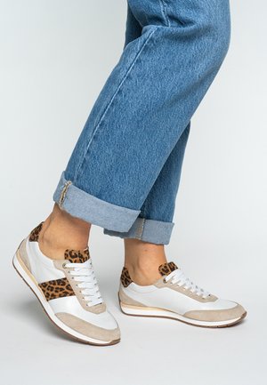 White leather sneakers with beige suede accents and leopard print details on the heel. The design features laces and a rubber sole.