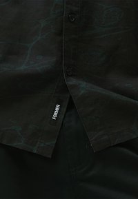 Black shirt with a subtle green pattern, featuring button closures and a tag labeled "FORMER" on the lower side.