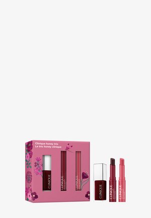 Clinique Honey Trio geschenkset met donkere besnagellak en twee tinten rode en roze lippenstiften op een witte achtergrond.