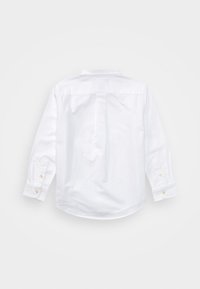 Camicia bianca a maniche lunghe in cotone. Presenta un colletto classico, polsini con bottoni e una piega centrale sulla schiena per facilitare i movimenti.