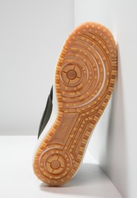 Nike sneaker sole with a textured, rubber design. Features concentric circles, star-shaped patterns, and an orange color with beige accents.