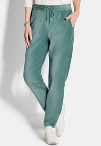 Lichtgroene corduroy joggerbroeken met elastische tailleband, verstelbare trekkoord en twee zijzakken. Draagt met witte sport sneakers.