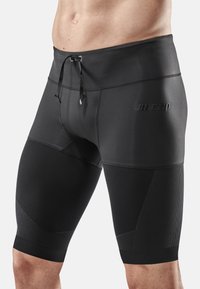 Shorts de compression noirs avec un design ajusté, une taille élastique, un cordon de serrage et des accents de panneaux texturés sur les jambes.