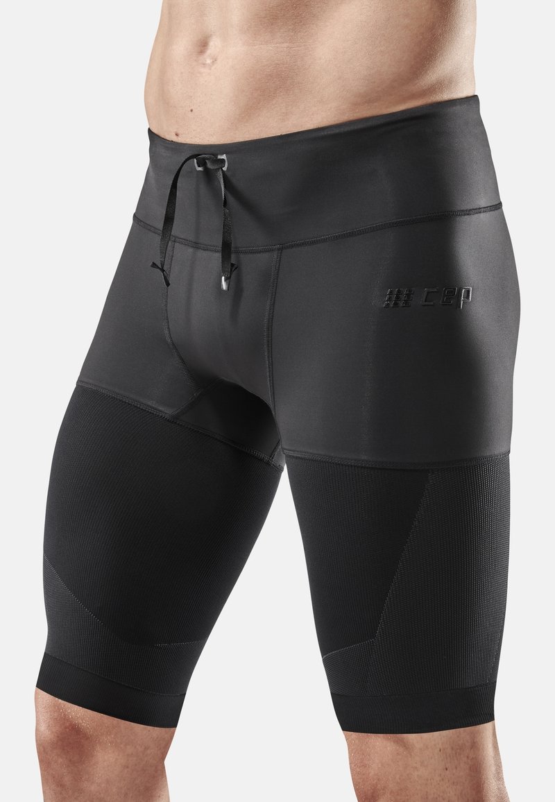 Schwarze Kompressionsshorts mit tailliertem Design, elastischem Bund, Kordelzug und strukturierten Paneelen an den Beinen.