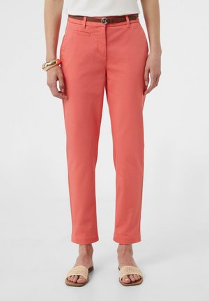 Korrallefarbene Chinohosen mit geraden Beinen, vorderen Taschen und einem braunen Gürtel. Kombiniert mit beigen offenen Sandalen für einen lässigen Look.