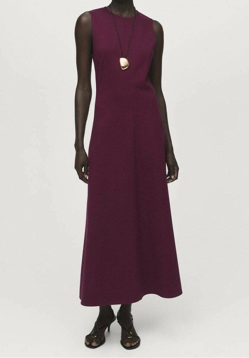 Robe prune sans manches et longue jusqu'au sol, portée avec des talons ouverts noirs et un long collier avec un grand pendentif.