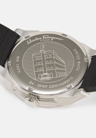 Roostevabast terasest kell musta kummirihmaga; tagaküljel on graveeritud hoone ja samba kujutis, millel on sildid "SWISS MADE" ja "WR 100m".