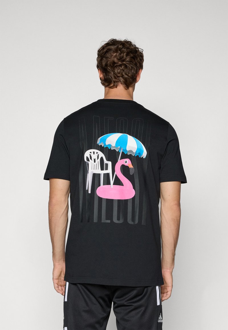 Sort t-shirt med et grafisk tryk af en pink flamingo, en hvid stol og en blå- og hvidstribet parasol på bagsiden. Blødt stof.