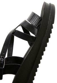Sandale à plateforme en cuir noir avec plusieurs brides et une boucle texturée, dotée d'une semelle épaisse et rainurée.