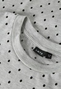 Graues T-Shirt mit kleinen schwarzen Punkten, Rundhalsausschnitt und weicher Textur. Sichtbares Etikett mit dem Markennamen "LMTD" und Größenangabe.