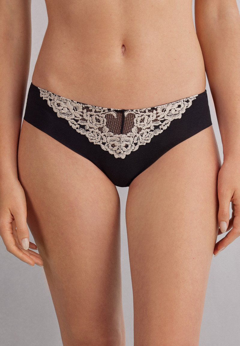 Zwarte kanten slipjes met een bloemenkantafwerking aan de voorkant en een gaas inzet. Zachte, gladde stof voor comfort. Hoog opgesneden ontwerp.