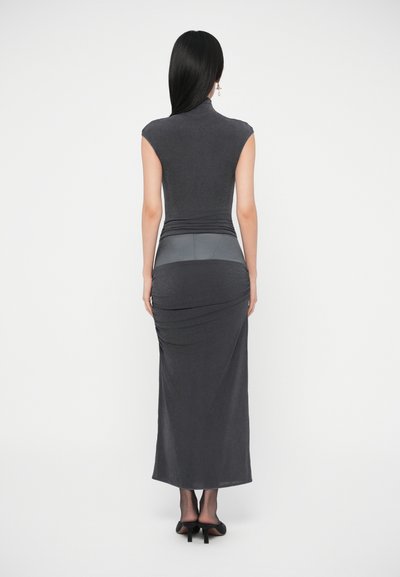 Szürke testhez simuló ruha magas nyakkal és vállat takaró rövid ujjakkal, ráncolt derékkal és hosszú szoknyával. Sima textúra, testhez álló sziluett.