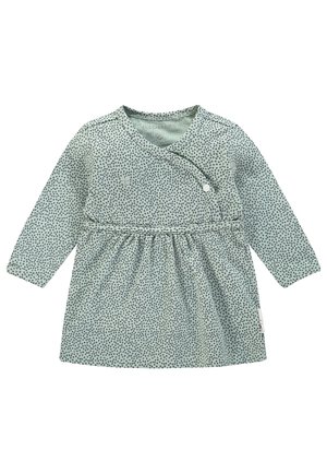 Robe bébé à manches longues avec des pois verts, devant style portefeuille fixé par un seul bouton pression blanc.
