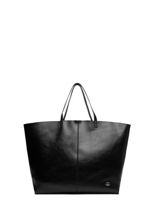 Bolso tote grande de cuero negro con asas dobles y un pequeño logo metálico en la esquina inferior derecha.