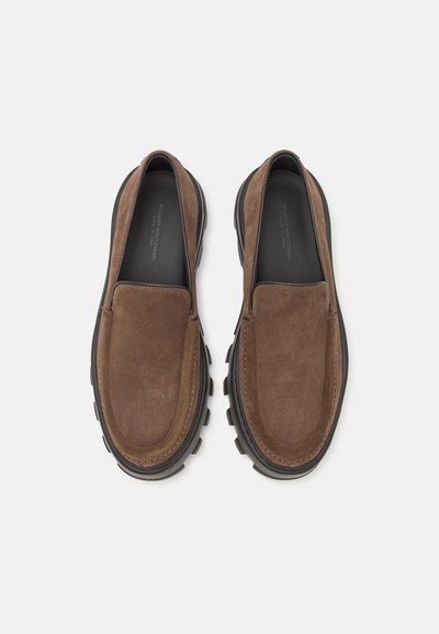 Braune Wildleder Slipper mit runder Zehenpartie, schwarzer Gummisohle und minimalen Nähdetails, entworfen für Komfort und einfache Handhabung.