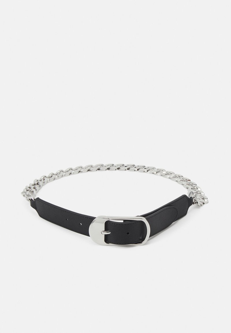 Ceinture en cuir noir et chaîne en métal argenté avec une grande boucle argentée posée à plat sur un fond blanc.