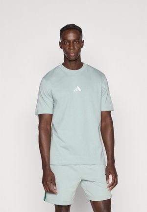 Camiseta de algodón verde claro con cuello redondo y mangas cortas, con un pequeño logo blanco de Adidas en el pecho.