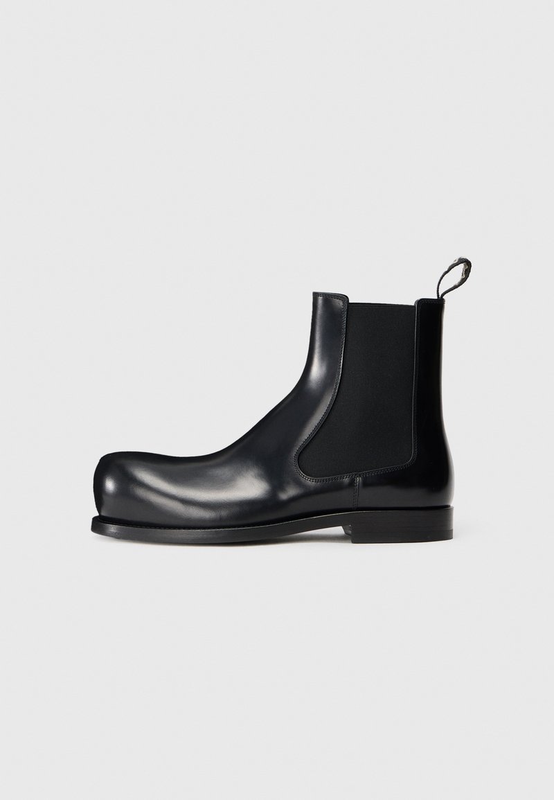 Stivale Chelsea in pelle nera con pannelli laterali elastici, punta arrotondata e suola testurizzata. Il design enfatizza un profilo elegante e moderno.