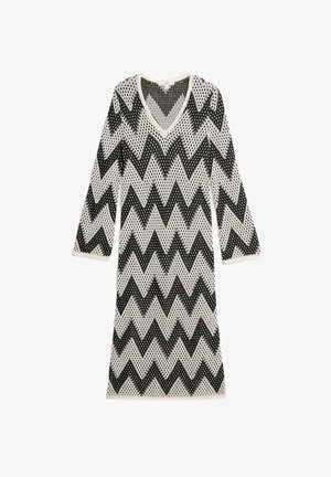 Abito lavorato a maglia bianco e nero a zigzag con maniche a tre quarti e scollatura a V, caratterizzato da una trama a intreccio aperto.