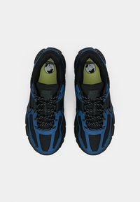 Par de sapatilhas desportivas Nike pretas e azuis com atacadores pretos padrões, vistas de cima sobre um fundo branco.