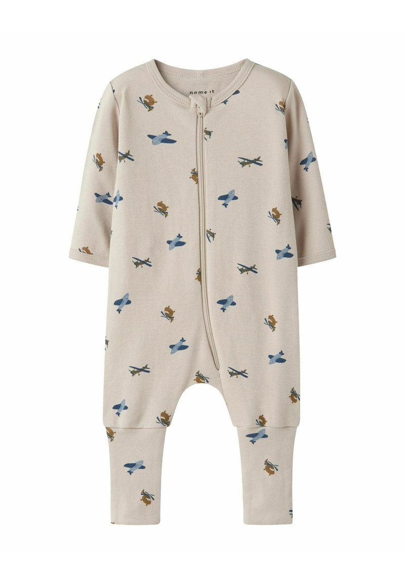 Combinaison en coton beige avec manches longues et fermeture éclair à l'avant, présentant des motifs d'avions bleus et d'écureuils bruns. Tissu doux et extensible.