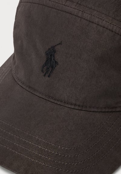 Tmavohnedý klobúk typu bucket s prešitým pásikom a malým čiernym vyšívaným logom hráča polo v strede prednej časti.