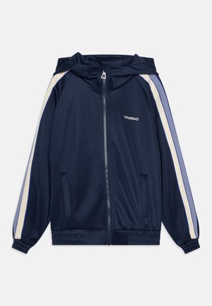 Tamsiai mėlynas sportinis džemperis su kapuce, užtrauktuku, kreminėmis šoninėmis juostelėmis, elastingais rankogaliais ir kišenėmis; pagamintas iš lygaus, lengvo audinio.