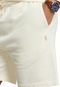 Bomullsshorts i ljusgul med elastisk midja, utrustad med en sidoficka och en liten broderad logotyp. Slät textur, klassisk passform.