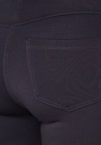 Dark stretch denim jeans with a fitted design, featuring a back pocket with contrasting stitching and a smooth texture.