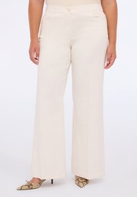 Pantaloni ampi di un beige chiaro realizzati in tessuto morbido con vita alta e due tasche laterali. Abbinati a tacchi a punta con stampa serpente.
