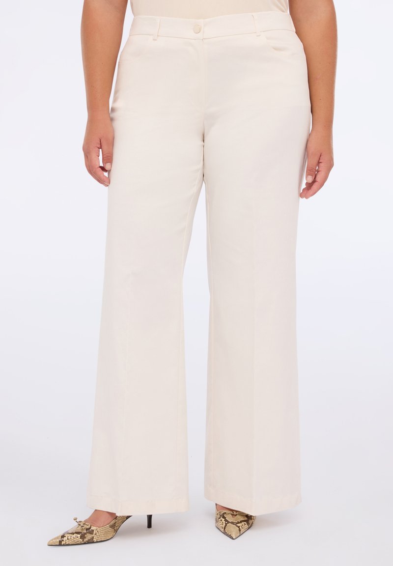 Pantaloni ampi di un beige chiaro realizzati in tessuto morbido con vita alta e due tasche laterali. Abbinati a tacchi a punta con stampa serpente.