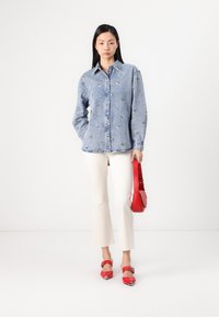 Τζιν πουκάμισο με λουλουδάτα κεντήματα, λευκά φαρδιά παντελόνια, κόκκινη τσάντα χειρός και κόκκινα τακούνια με μεταλλικές λεπτομέρειες. Απλός, καθημερινός σχεδιασμός ρούχου.