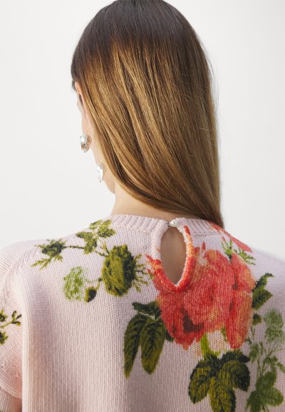 Pink knit sweater with floral design featuring green leaves and red roses. Back has a keyhole cutout, accented with a decorative button.