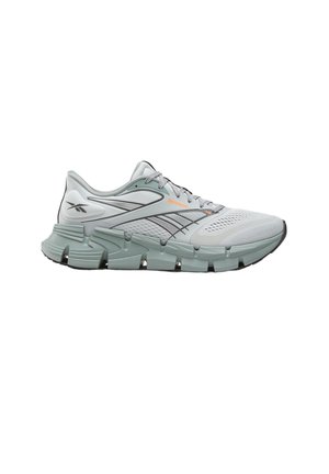 Lichtgrijze Reebok hardloopschoen met een bovenwerk van mesh, een dikke gesegmenteerde zool, zwarte accenten en een oranje logo aan de zijkant, gezien vanaf de buitenkant.