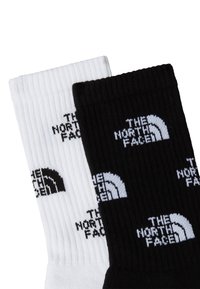 Bomull Crew-strumpor i svart och vitt med ribbad textur. The North Face-logotypen visas i kontrasterande färger på varje strumpa.