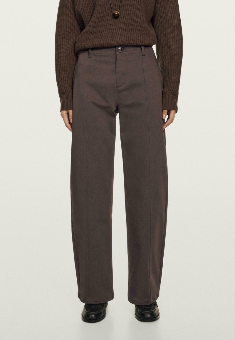 Brun ribbet sweater parret med høj talje, brede grå bukser med foran syninger, en knaplukning og en glat overflade.