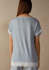 Lichtblauw kortemouwen top met een kantafwerking aan de mouwen en de onderrand. Zachte textuur en losse pasvorm met een minimalistisch ontwerp en ronde hals.